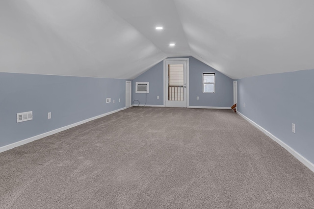 bonus room with vaulted ceiling, a wall mounted air conditioner, and light colored carpet