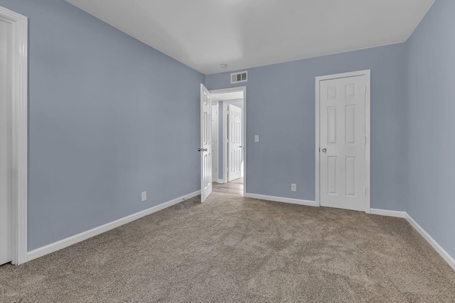 unfurnished bedroom with light colored carpet and a closet