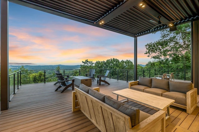 deck at dusk with ceiling fan and an outdoor hangout area