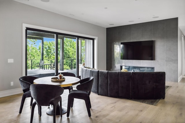 dining area with a tile fireplace and light wood-type flooring