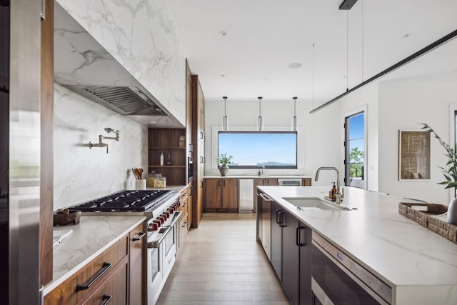 kitchen featuring decorative backsplash, pendant lighting, wall chimney exhaust hood, and sink