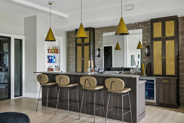 kitchen featuring kitchen peninsula, dark brown cabinetry, pendant lighting, light hardwood / wood-style floors, and a breakfast bar area