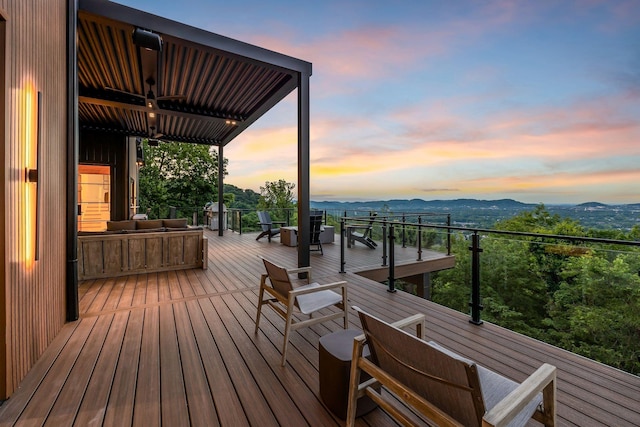 deck at dusk featuring a mountain view and ceiling fan