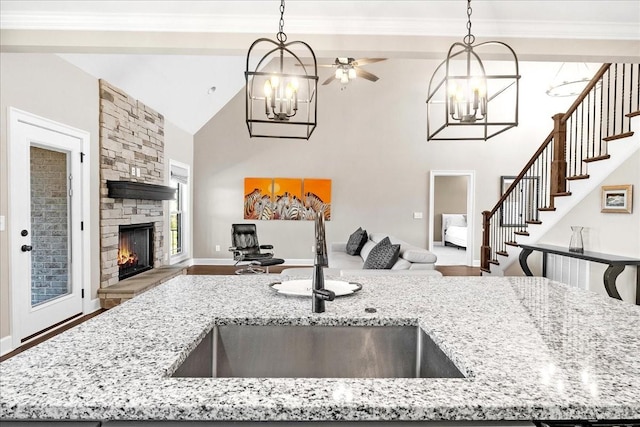 kitchen with a stone fireplace, light stone countertops, sink, and decorative light fixtures