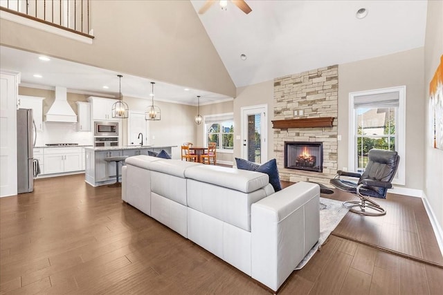 living room featuring a fireplace, dark hardwood / wood-style floors, high vaulted ceiling, and ceiling fan