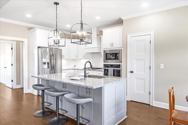 kitchen featuring white cabinets, appliances with stainless steel finishes, light stone countertops, and a kitchen island with sink