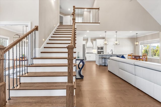 stairway with hardwood / wood-style floors, ornamental molding, and sink