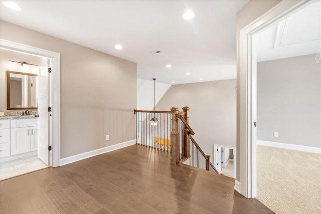 hallway featuring sink, wood-type flooring, and vaulted ceiling