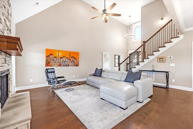 living room featuring a fireplace, high vaulted ceiling, dark wood-type flooring, and ceiling fan with notable chandelier