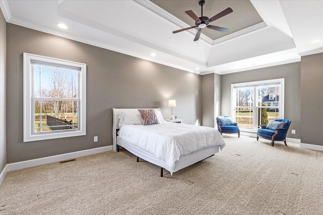 bedroom featuring ceiling fan, a raised ceiling, carpet floors, and multiple windows