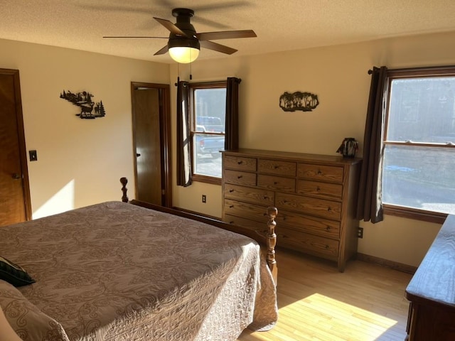 bedroom featuring ceiling fan, light hardwood / wood-style flooring, and a textured ceiling