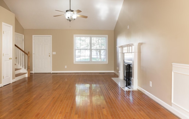 unfurnished living room with hardwood / wood-style flooring, a tiled fireplace, lofted ceiling, and ceiling fan