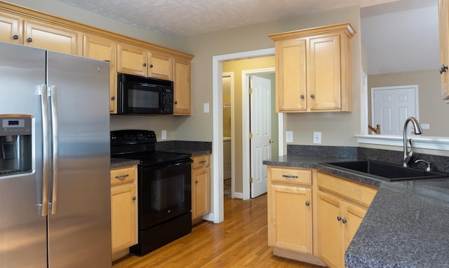 kitchen with light brown cabinetry, sink, light hardwood / wood-style flooring, and black appliances