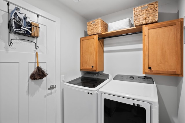 clothes washing area with cabinets and washer and dryer