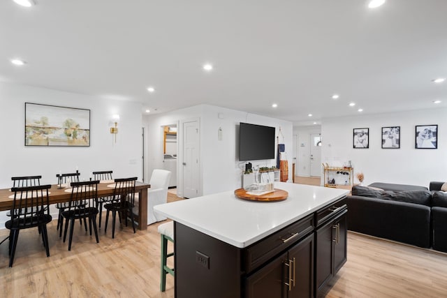 kitchen with light wood-type flooring, washer / clothes dryer, a kitchen island, and a breakfast bar area