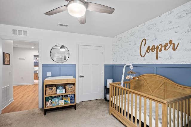 bedroom featuring ceiling fan, carpet, and a nursery area