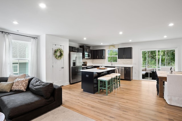 kitchen with appliances with stainless steel finishes, sink, light hardwood / wood-style flooring, a center island, and a breakfast bar area