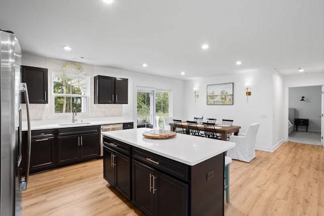 kitchen with stainless steel fridge, tasteful backsplash, sink, light hardwood / wood-style floors, and a kitchen island