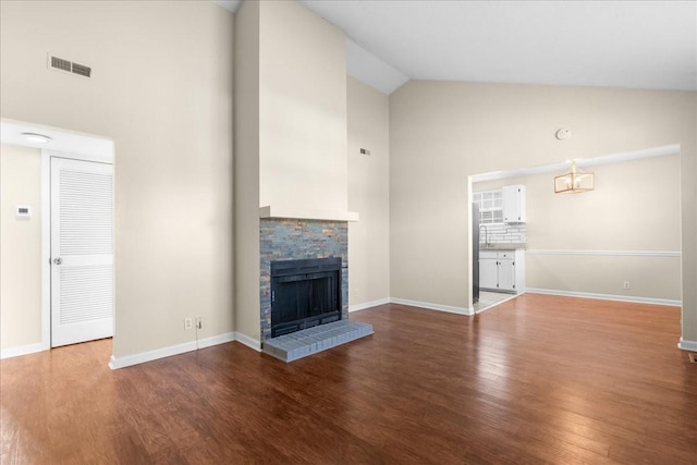 unfurnished living room featuring wood-type flooring, high vaulted ceiling, and a brick fireplace