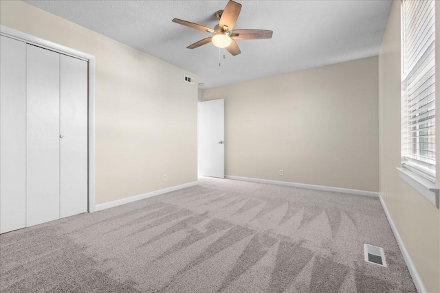 unfurnished bedroom with ceiling fan, a closet, carpet, and a textured ceiling