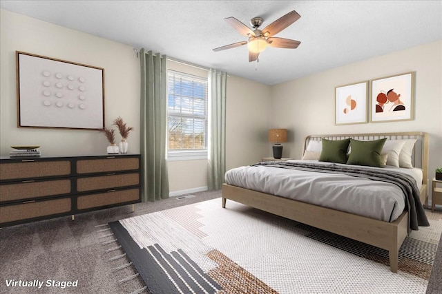 bedroom with ceiling fan, dark carpet, and a textured ceiling