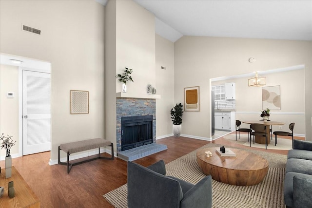 living room with hardwood / wood-style flooring, high vaulted ceiling, and a brick fireplace