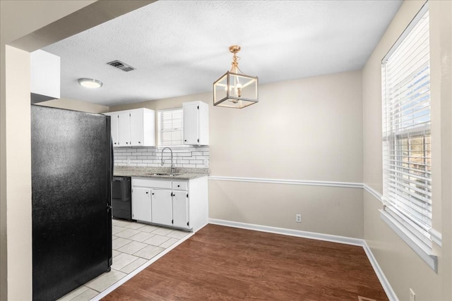 kitchen with black appliances, decorative light fixtures, white cabinetry, and sink