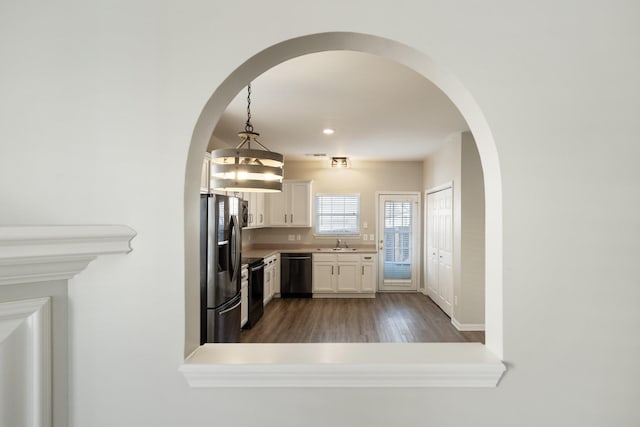 kitchen with white cabinetry, sink, dark wood-type flooring, pendant lighting, and black appliances