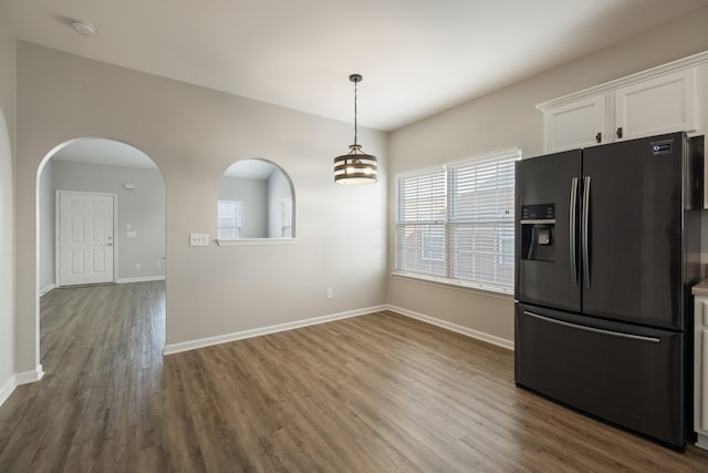 kitchen with hardwood / wood-style floors, white cabinets, stainless steel refrigerator with ice dispenser, hanging light fixtures, and a notable chandelier