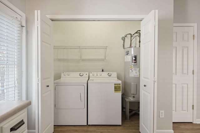 clothes washing area featuring washer and clothes dryer, hardwood / wood-style flooring, and water heater