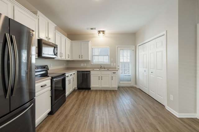 kitchen featuring white cabinetry, sink, light hardwood / wood-style floors, and appliances with stainless steel finishes