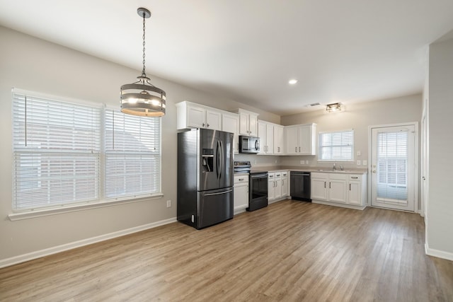 kitchen with pendant lighting, light hardwood / wood-style floors, white cabinetry, and stainless steel appliances