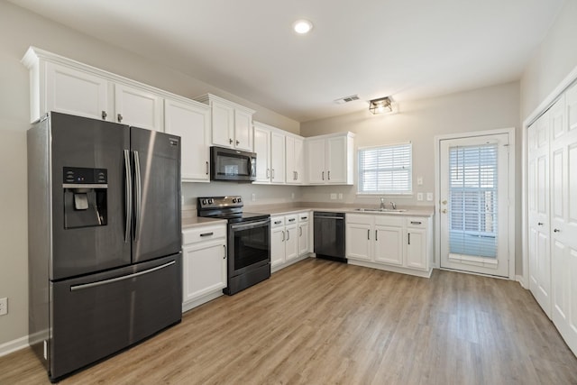 kitchen featuring white cabinets, sink, stainless steel appliances, and light hardwood / wood-style flooring