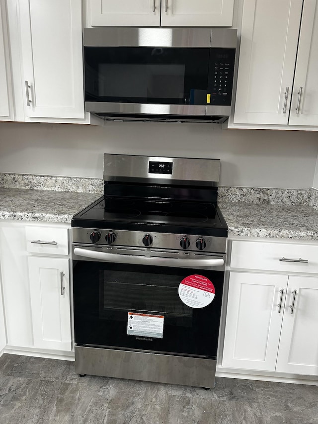 kitchen with white cabinetry, stainless steel appliances, and light stone counters