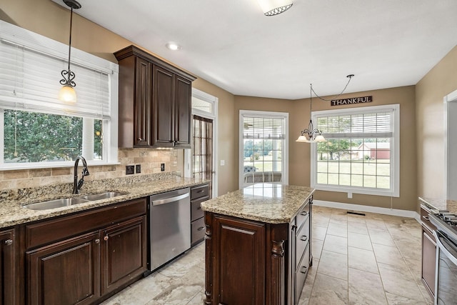 kitchen with light stone countertops, stainless steel appliances, sink, decorative light fixtures, and an inviting chandelier