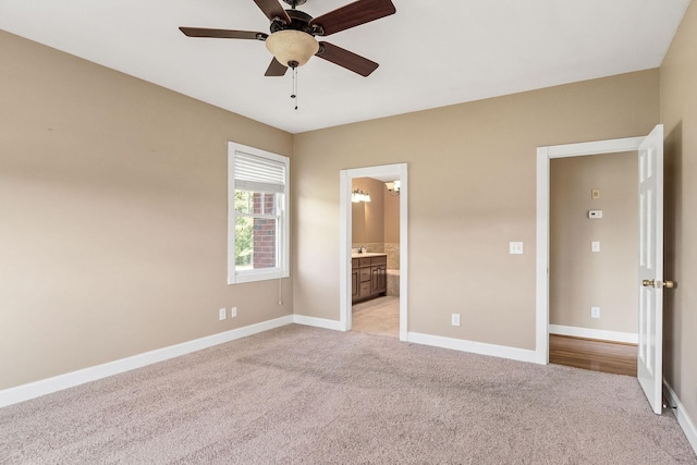 unfurnished bedroom featuring connected bathroom, light colored carpet, and ceiling fan