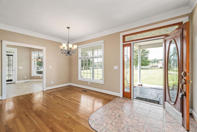 entryway with light hardwood / wood-style floors, crown molding, and an inviting chandelier