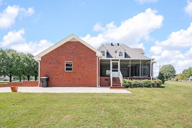 rear view of house with a patio, a lawn, and a sunroom