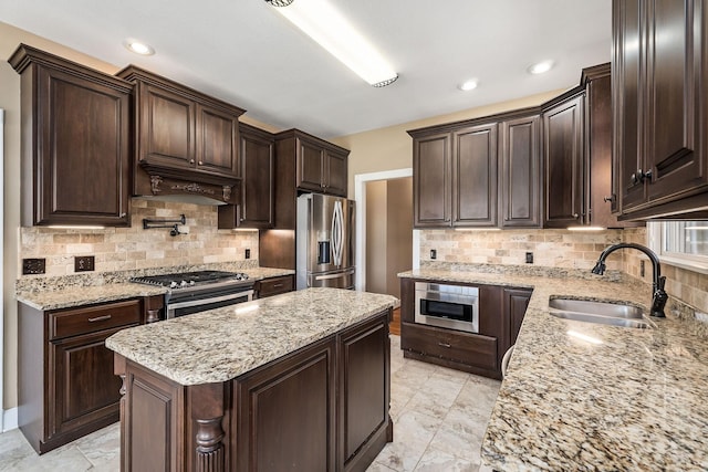 kitchen with a kitchen island, sink, light stone countertops, and stainless steel appliances