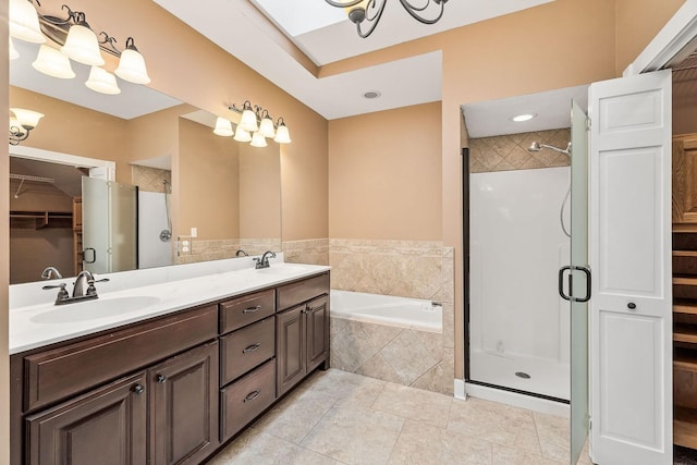 bathroom with tile patterned flooring, shower with separate bathtub, vanity, and a skylight