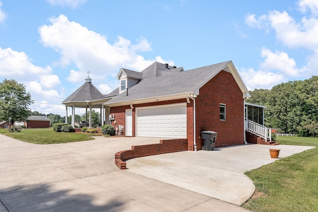 view of side of home featuring a garage, a lawn, and a sunroom