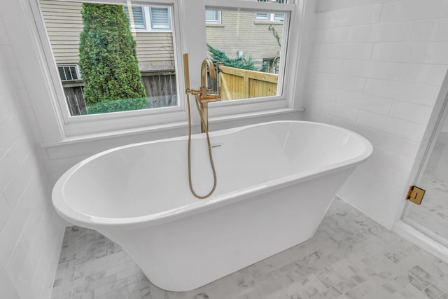 bathroom featuring a bath and tile walls