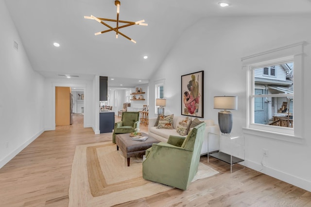 living room with high vaulted ceiling, a chandelier, and light wood-type flooring