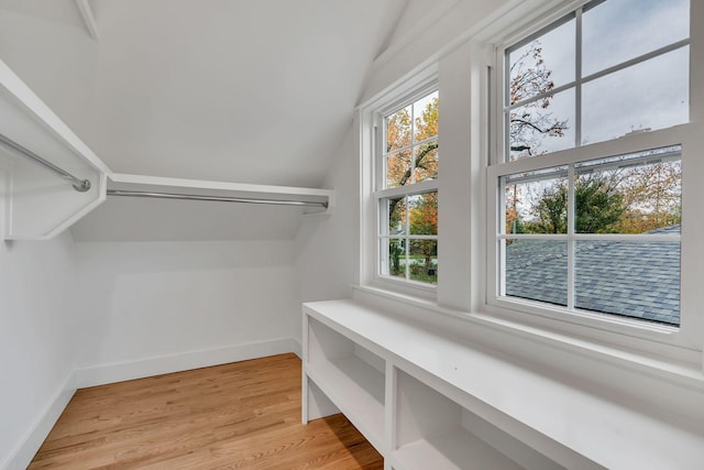 spacious closet with light hardwood / wood-style flooring and vaulted ceiling