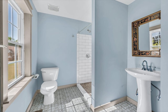 bathroom with a tile shower, toilet, and sink