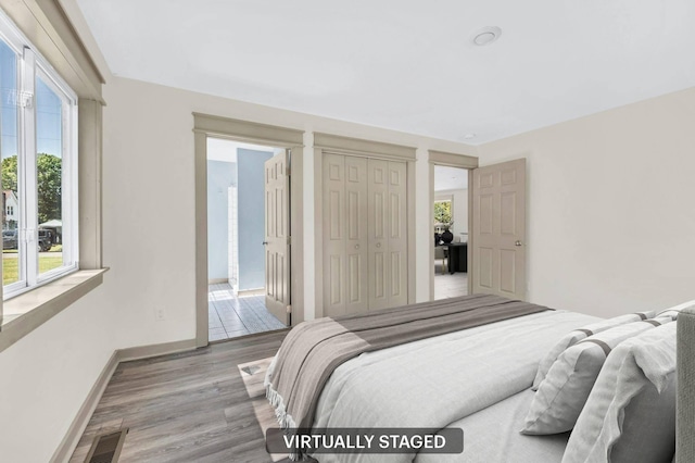 bedroom with multiple windows, a closet, and light hardwood / wood-style flooring