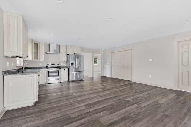 kitchen featuring sink, wall chimney range hood, dark hardwood / wood-style floors, dark stone countertops, and appliances with stainless steel finishes