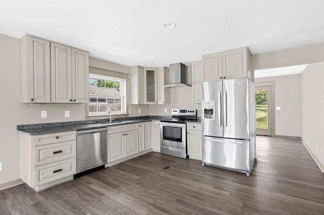 kitchen with wall chimney exhaust hood, dark hardwood / wood-style flooring, sink, and stainless steel appliances