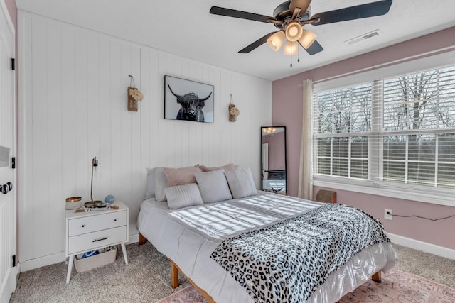 bedroom with light carpet, ceiling fan, and wood walls