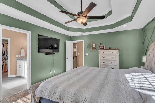 bedroom featuring ceiling fan, a raised ceiling, crown molding, a walk in closet, and a closet